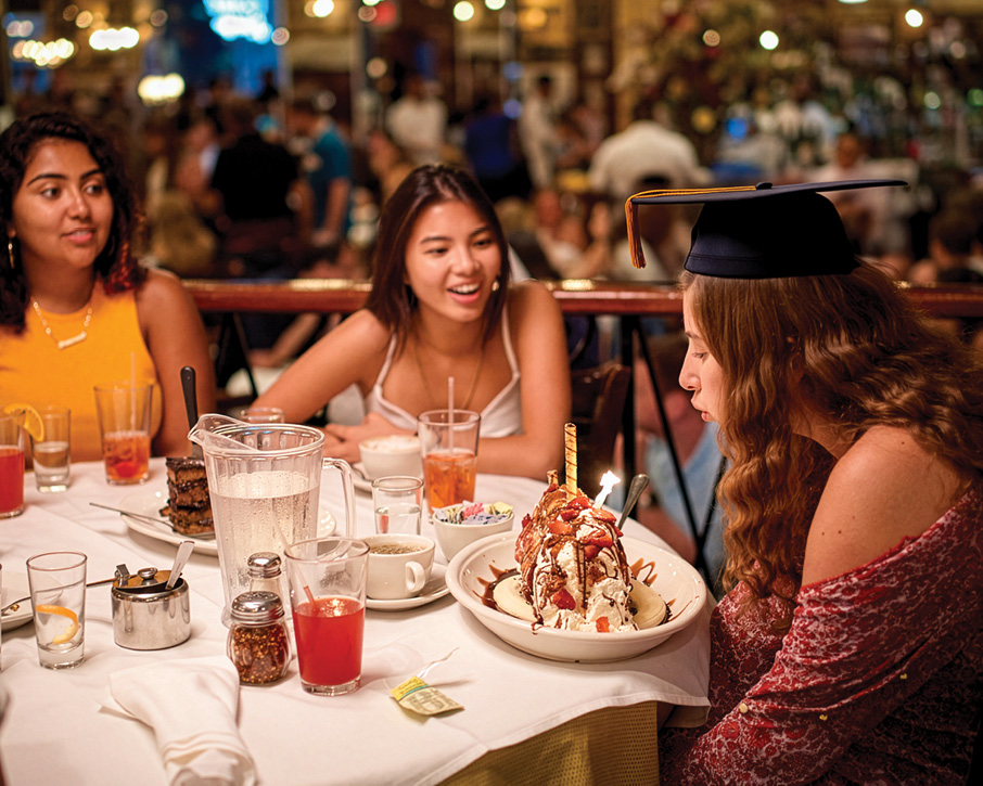 Three people celebrating their graduation at Carmine's NYC
